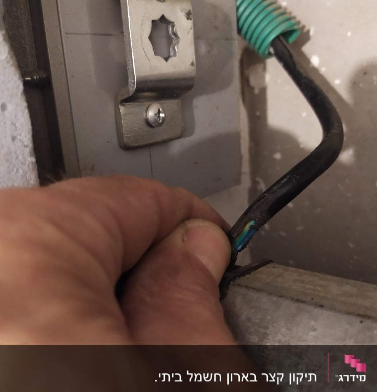 יד מחזיקה חוט חשמל שחור עם בידוד ירוק